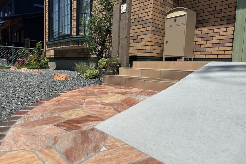 富士市の新築外構アプローチ施工事例。刷毛引き仕上げコンクリートスロープと乱形石敷設で可愛らしいデザインを実現。